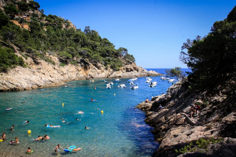 people swimming in blue ocean next to an cliff