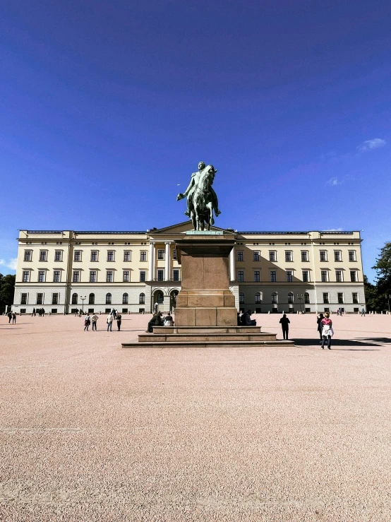 a statue in front of a white building and a blue sky