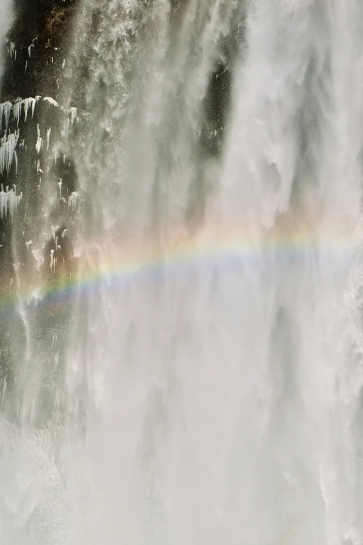 a rainbow in front of a waterfall with water