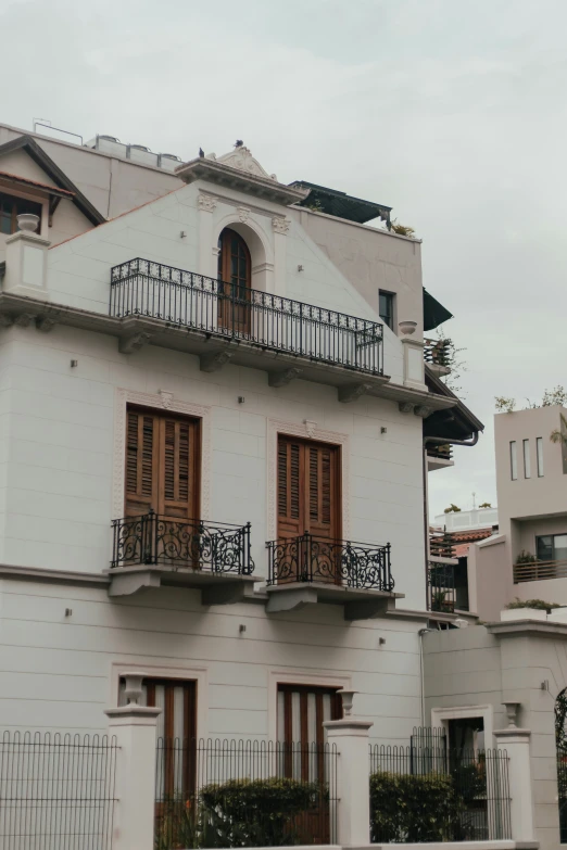 a white building with a black iron balcony railing and windows