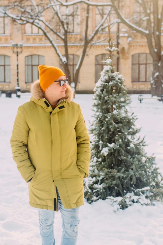 a man in snow gear standing next to a tree