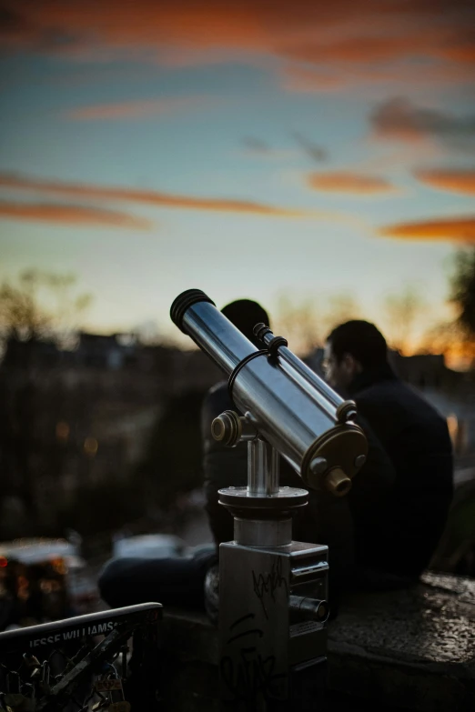 two men are sitting looking through a telescope