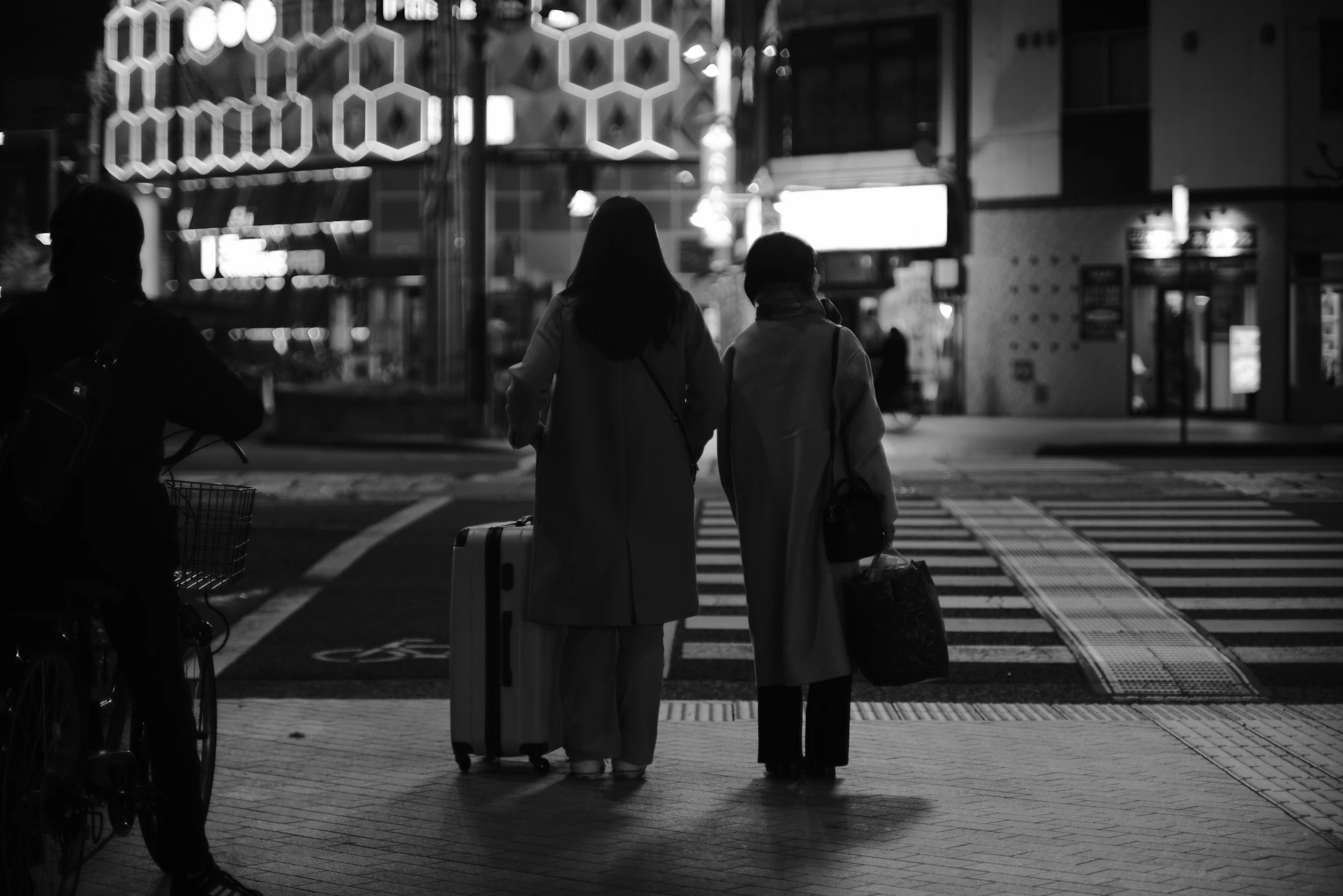 a woman and man walk past an empty street with luggage