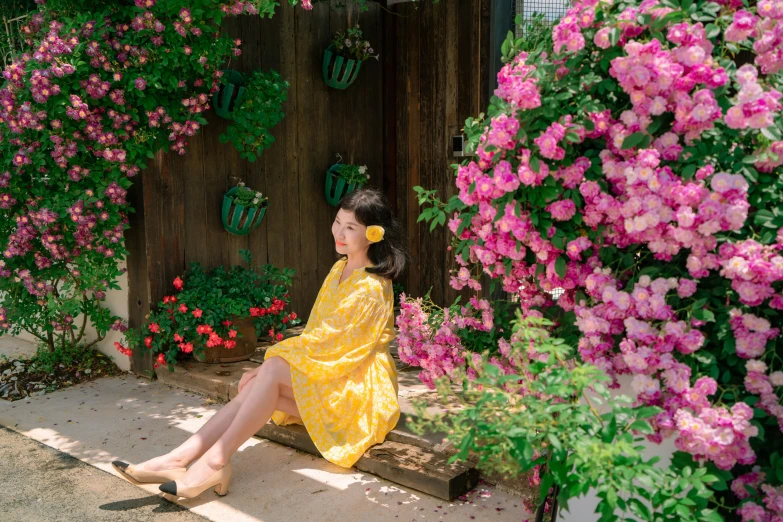 a woman is sitting outside in a dress with pink flowers