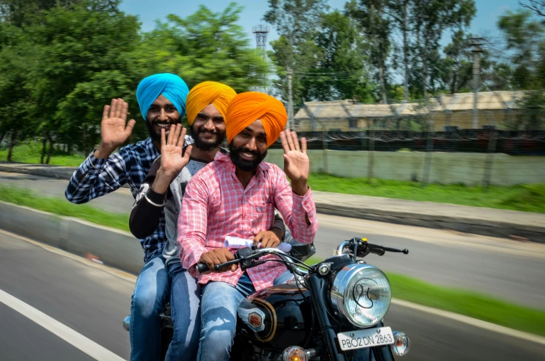 a man rides with two other men on his motorcycle