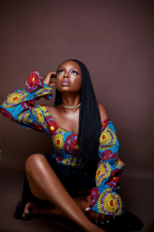 a black woman in african print sitting on the floor