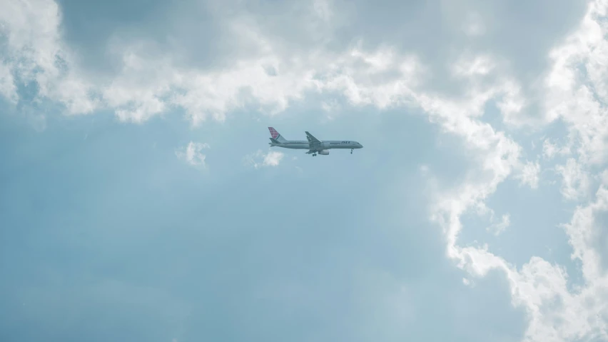 an airplane flying in the sky, some fluffy clouds behind it