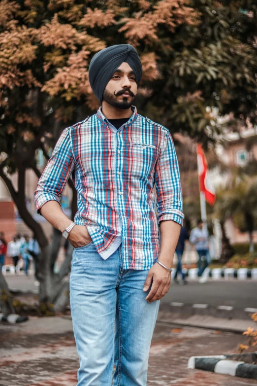 a man in striped shirt and blue jeans standing next to trees