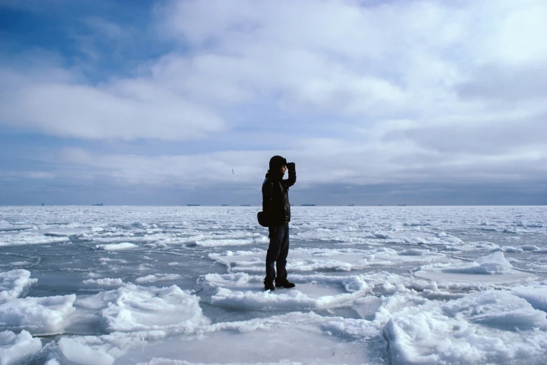 a man standing on the ice while he talks on his phone