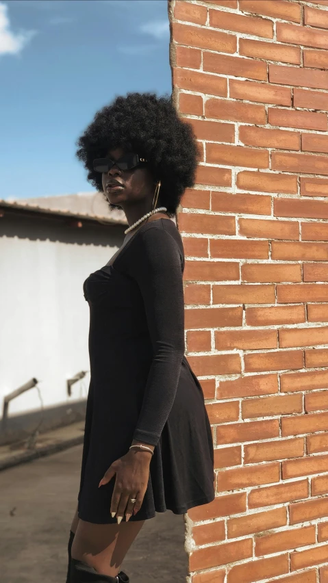 a woman leaning against a brick wall in heels