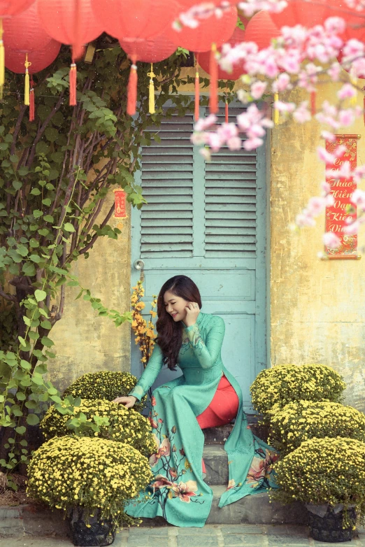 woman wearing long dress standing near plant with flowers