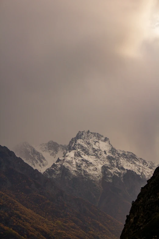 a mountain covered in snow under a cloudy sky