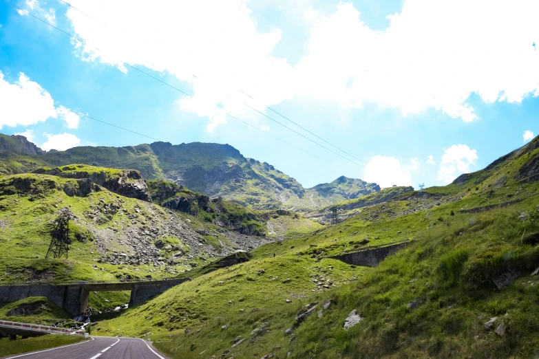 a view of a very lush green hill side with some rocks and grass