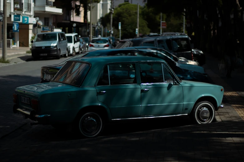 a green car sitting on the side of a road