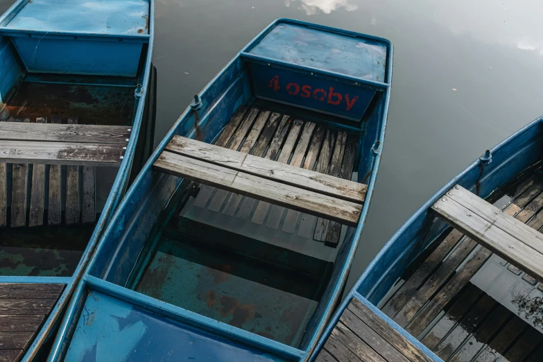 the three different sized wooden boats are tied up