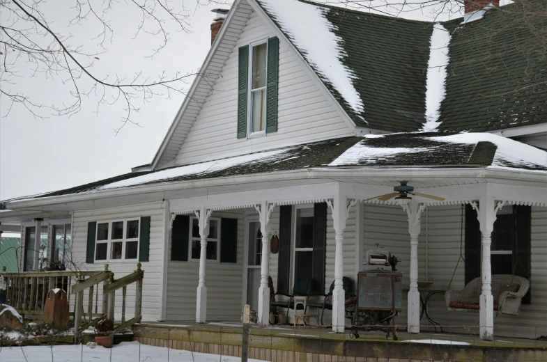 a white house with an attached veranda and lots of snow