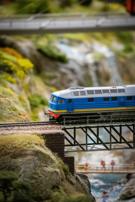 a blue and white train rides over a bridge