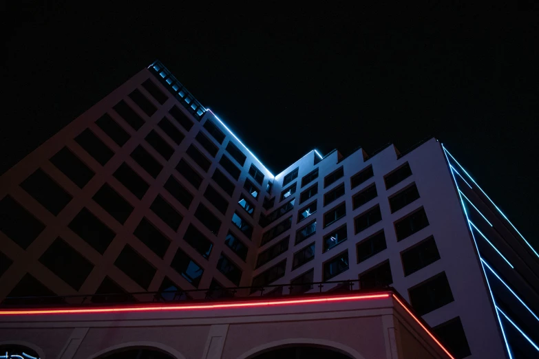 a large building with lights on its facade and buildings around it