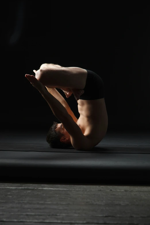 a man in black trunks is stretching his leg on the ground