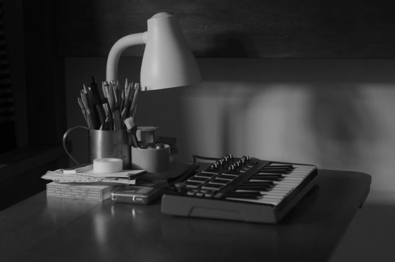 a desk with a lamp and a keyboard next to some papers