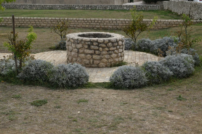 an empty stone fire pit in the middle of the garden