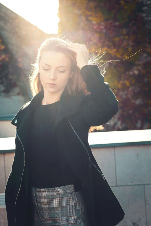 a woman stands outside holding her hair up