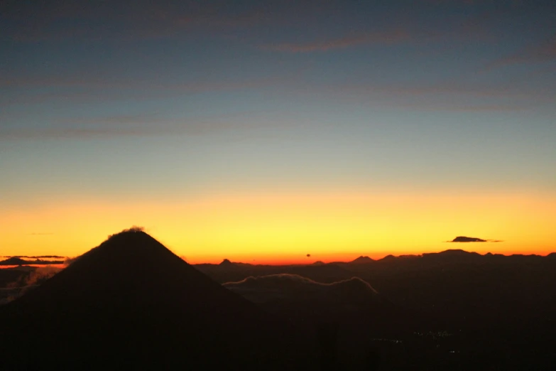 sunset from a distance with the silhouette of a mountain