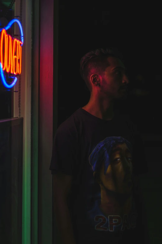 a man standing in front of a neon sign