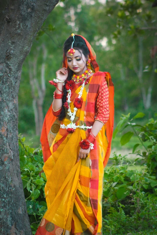 woman dressed in traditional clothing standing next to a tree