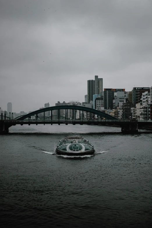 a speed boat floats in the water near a bridge