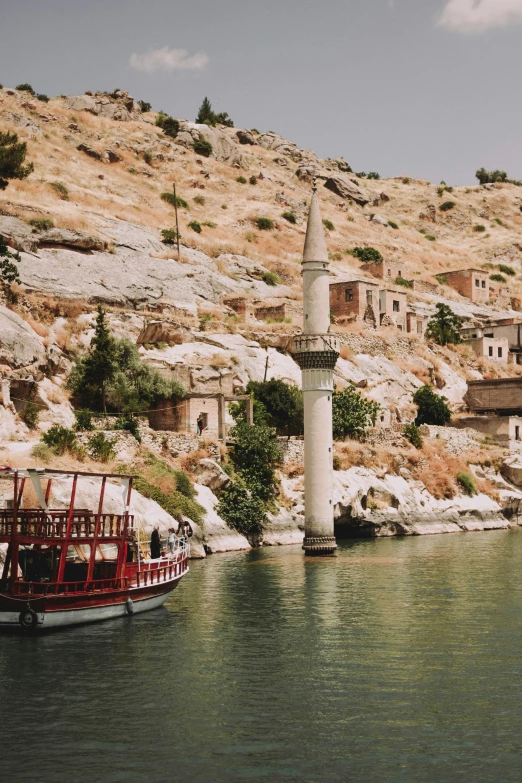 a boat traveling down the river near a large stone hill