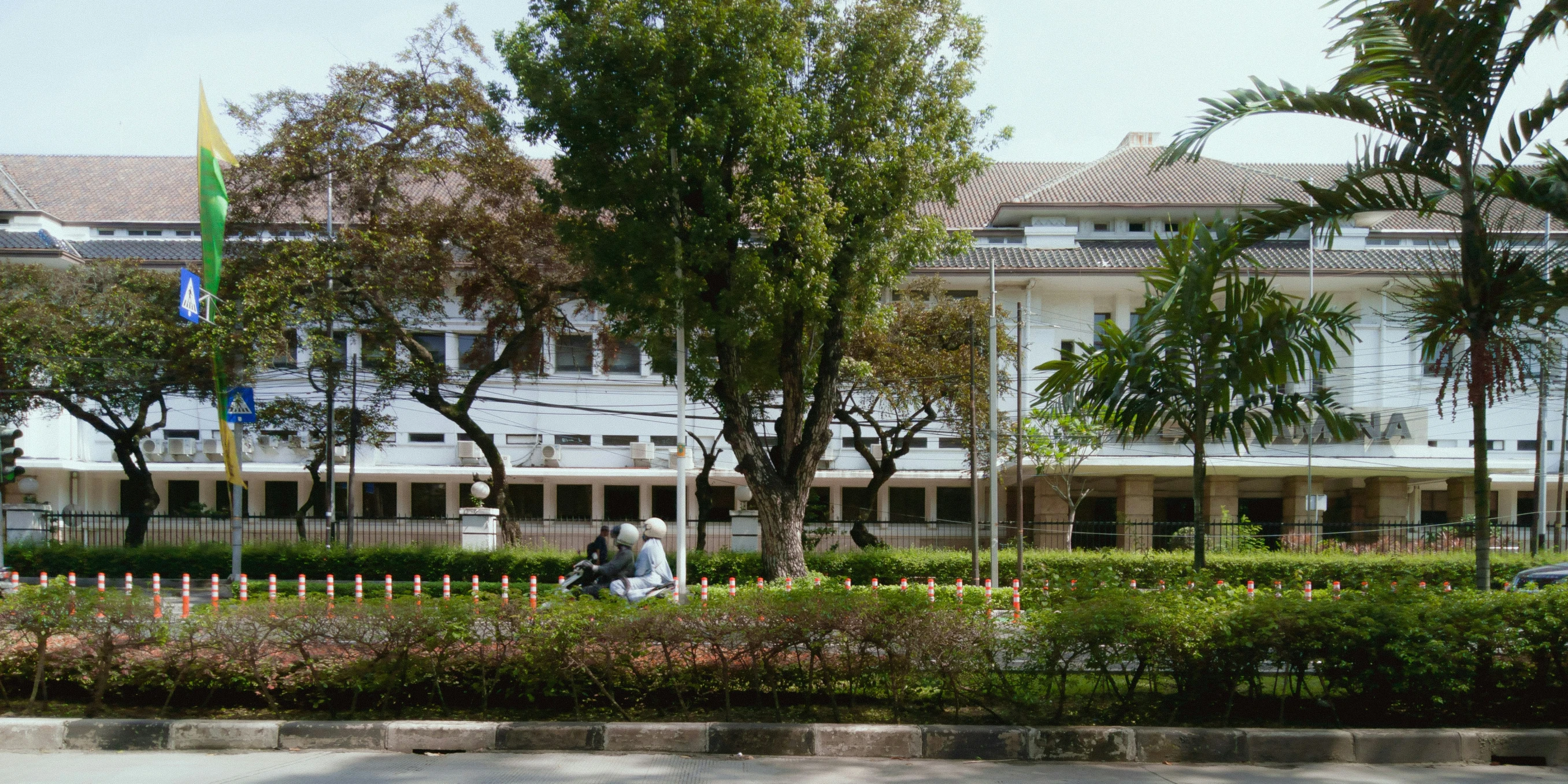 a white building next to trees and flowers