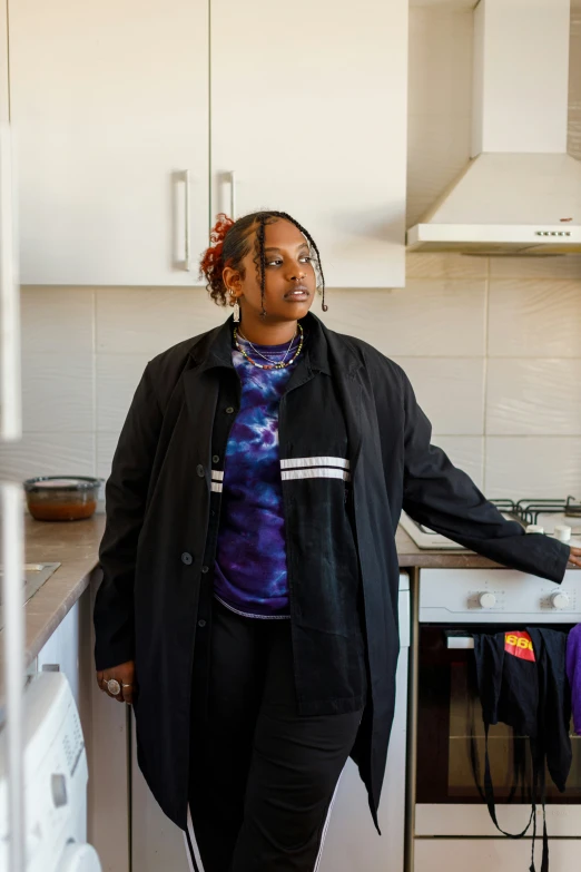 a woman standing at the edge of her kitchen in front of her oven