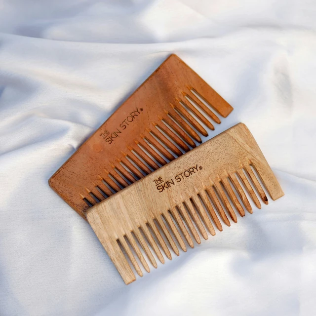 two wooden combs with engraved writing on the sides