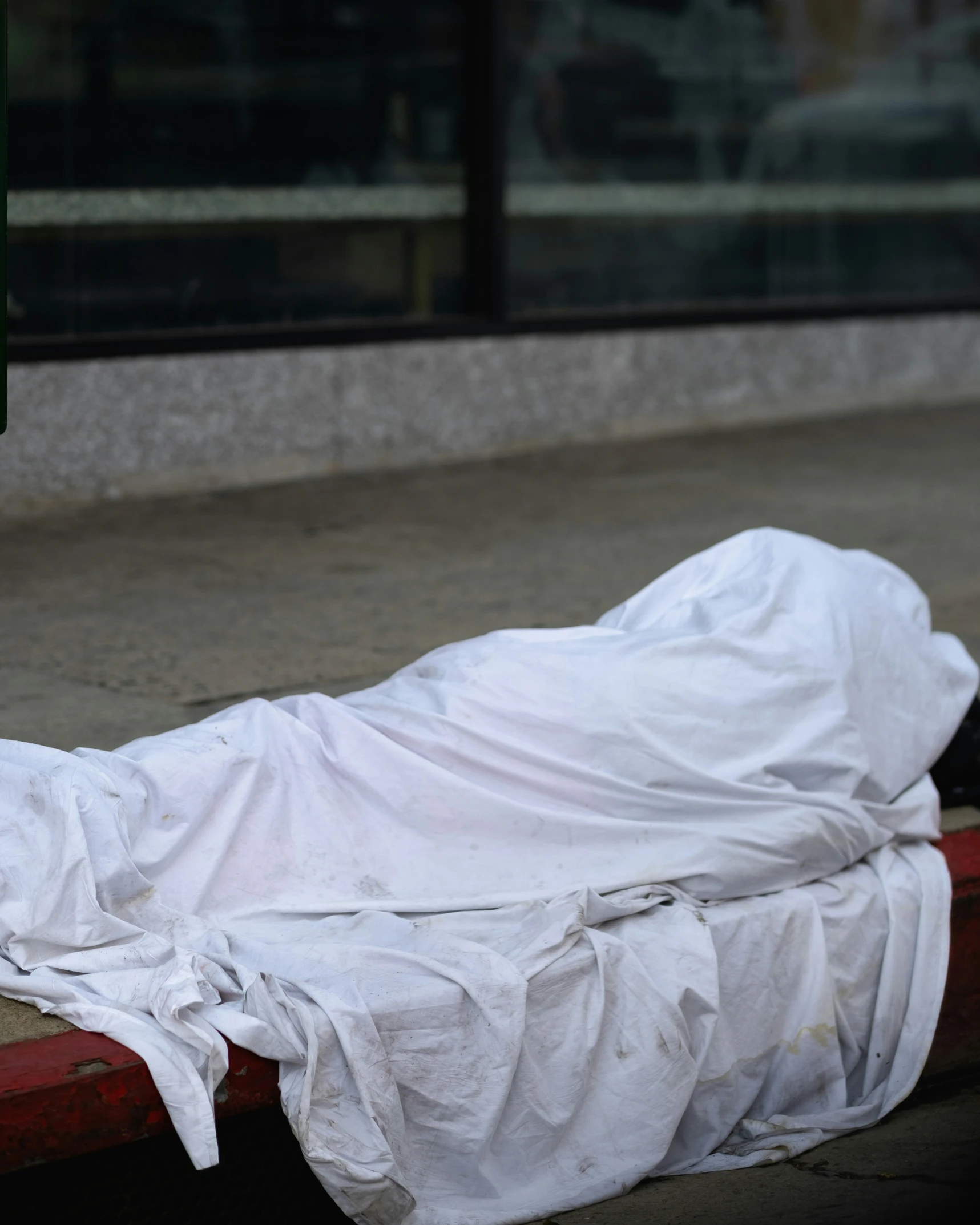 there is a body wrapped in white cloth laying on a red bench