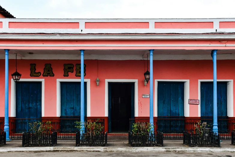 a pink and blue house with iron fencing