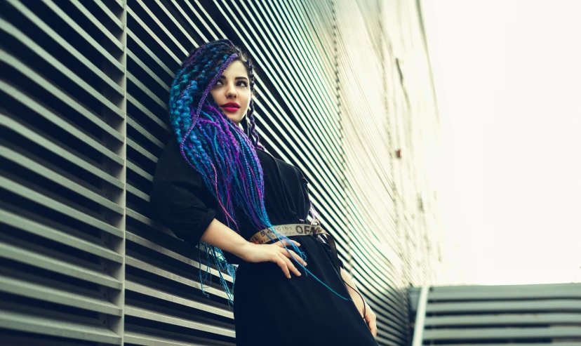 a woman leaning on a wall next to a building