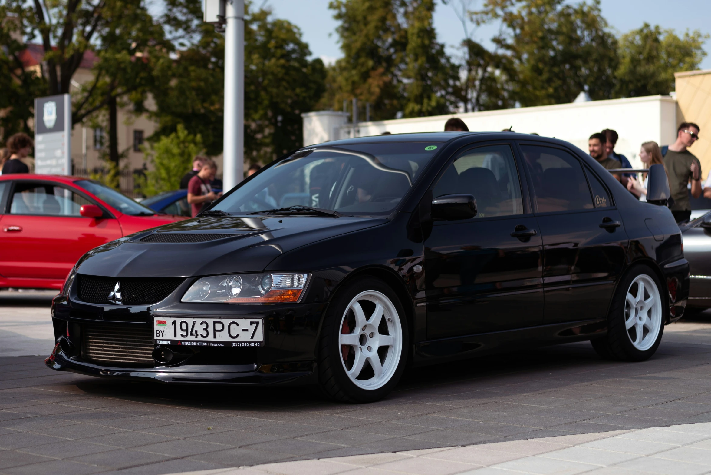 a black car with some white wheels and a man standing by