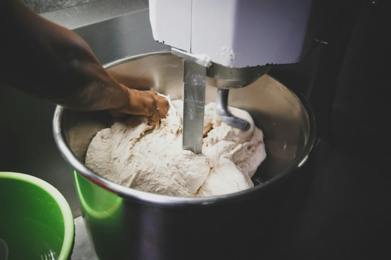 a person is making ice cream in a stainless steel bowl