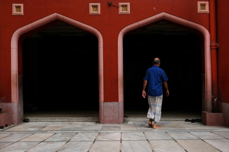 man with blue shirt standing near two archways