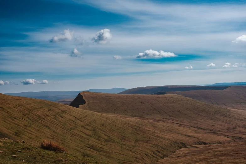 a hill top with a sky filled with clouds above it