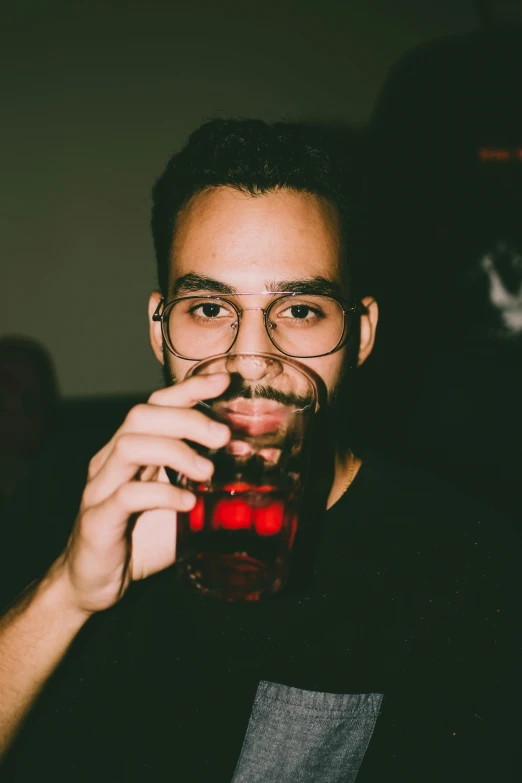 a man in glasses holds a red cup with liquid