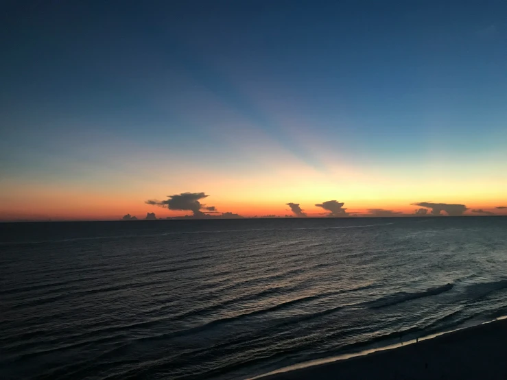 a beautiful sunrise at the beach with some clouds