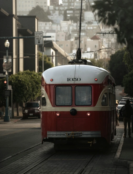 a red and white trolley car in front of a large city