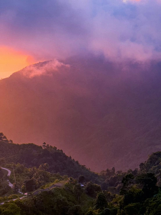 a view of the sky with clouds surrounding trees and a mountain