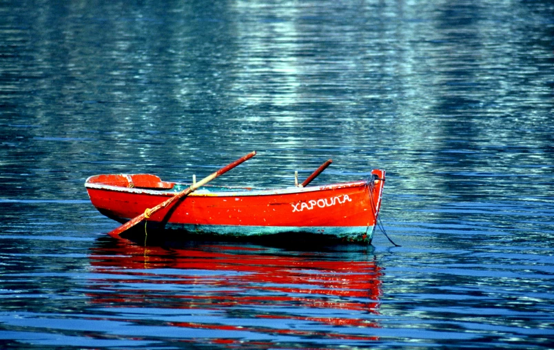 small wooden row boat sitting on calm water