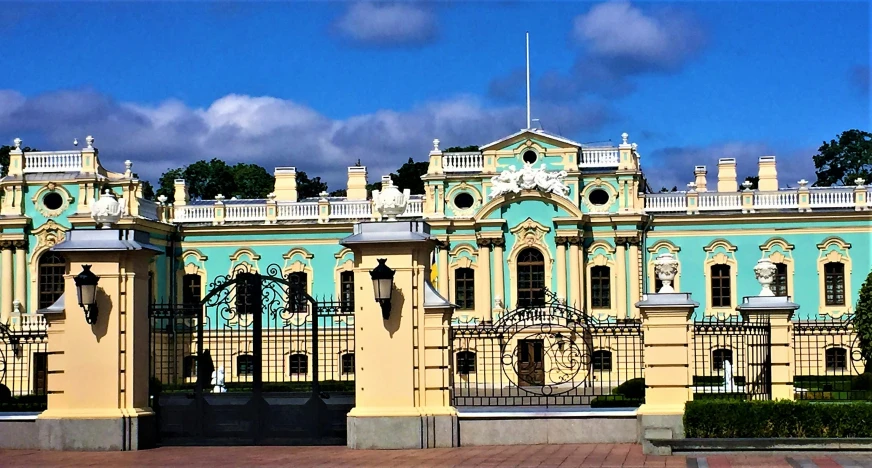 a blue and beige palace with iron fence