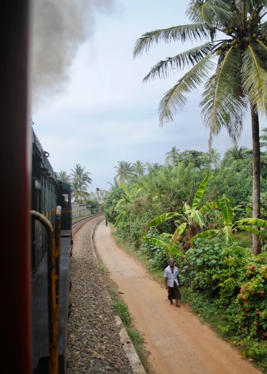 a train driving down the track towards a dirt road