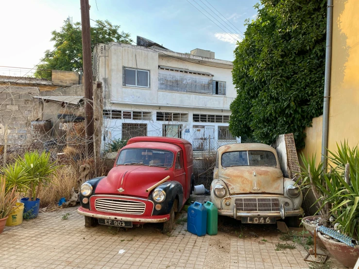 two old cars parked in the driveway of a house