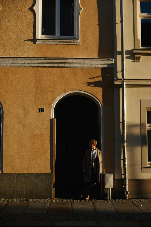 a person standing in the doorway to an orange colored building